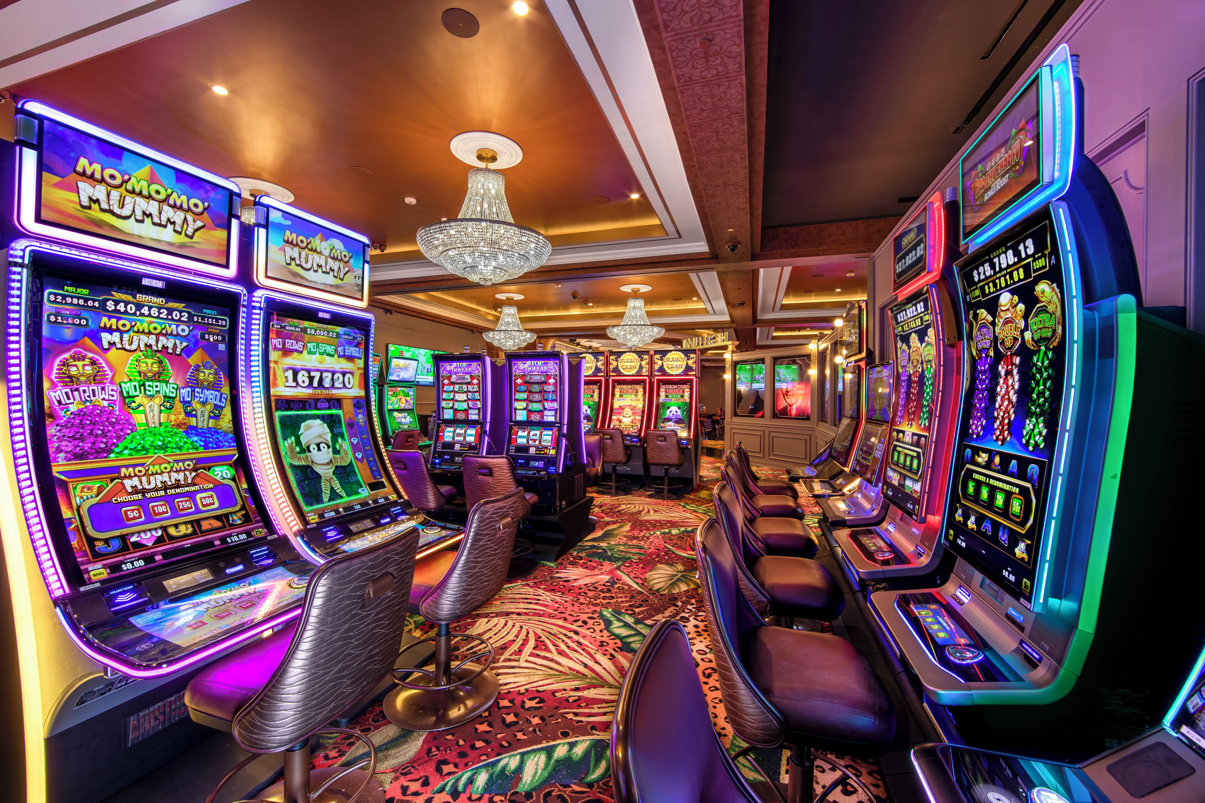 A casino with slot machines, leather chairs, and chandeliers.