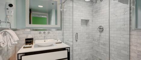 A modern bathroom with a glass-enclosed shower, a white sink, and a large mirror.