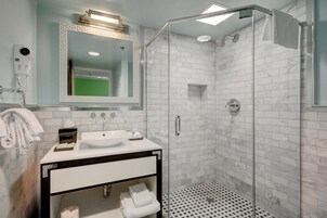 Uma casa de banho moderna com cabine de duche em vidro, lavatório branco e um espelho grande.