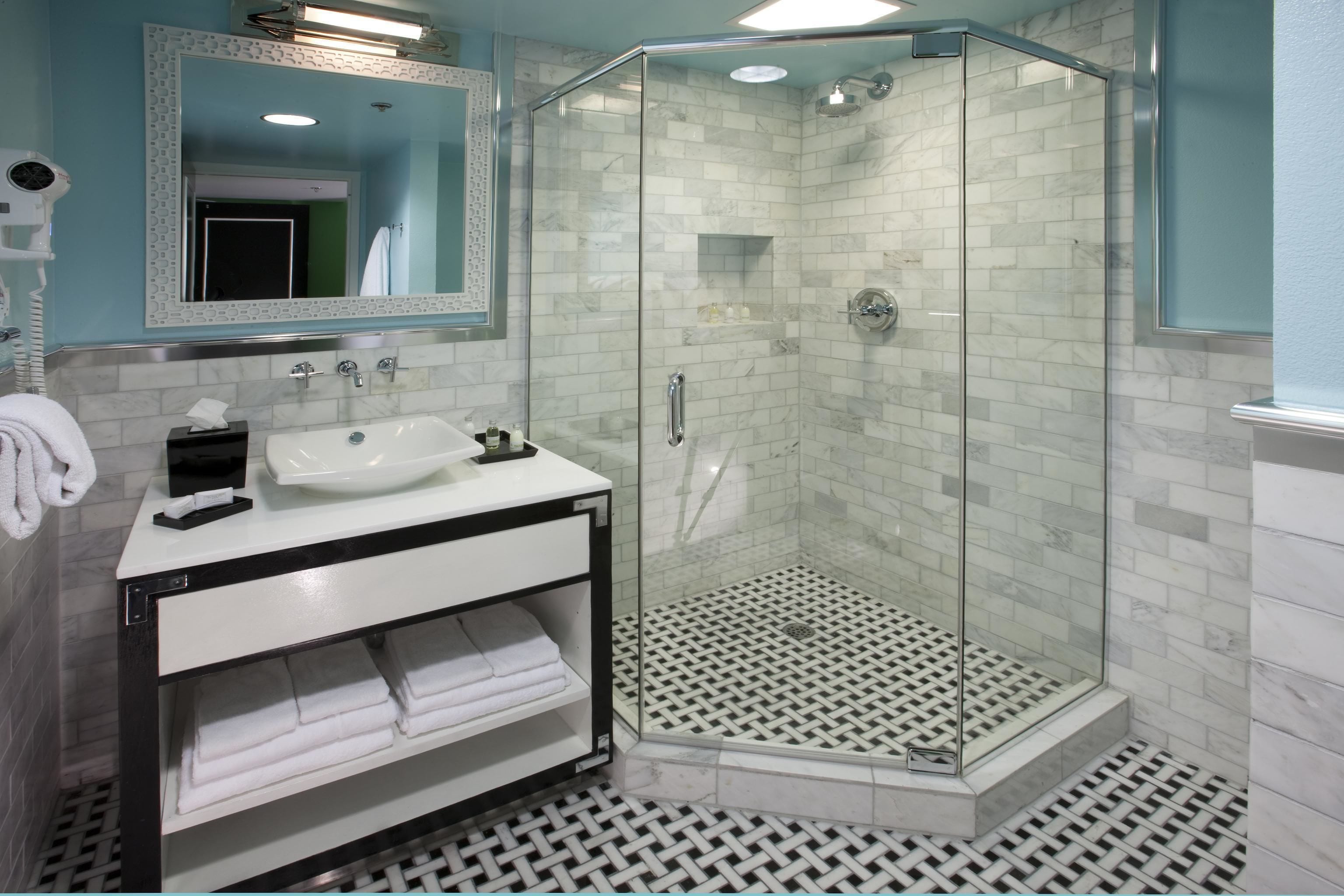 Een moderne badkamer met een douche met glazen wand, een wit wastafelmeubel en een spiegel met decoratieve lijst.
