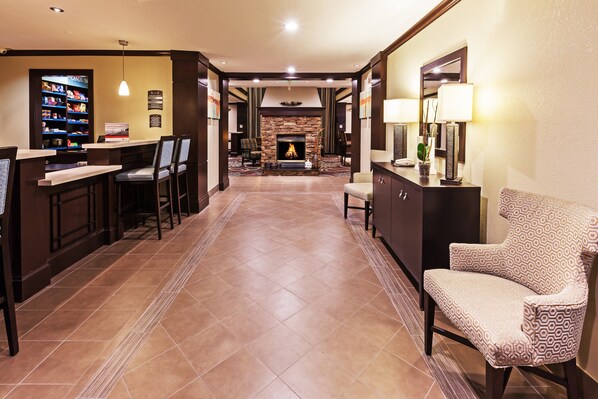 Un hall de hotel con zona de bar, asientos, chimenea y mostrador de recepción.