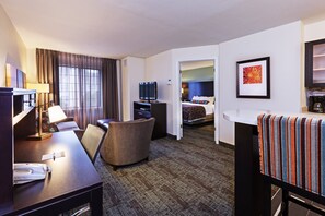 Relax in a stylish room with a sofa, armchair, and flat-screen TV, plus a desk and large window.