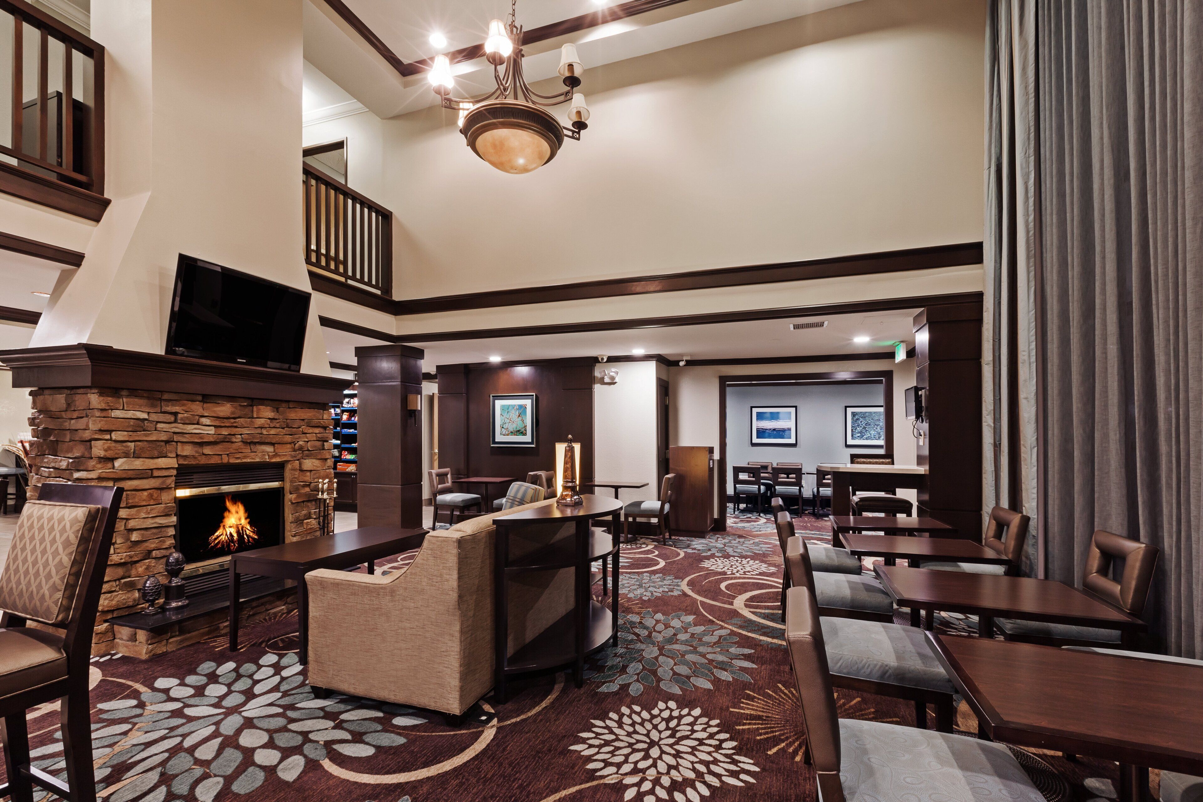 A hotel lobby with a fireplace, seating area, and a staircase.
