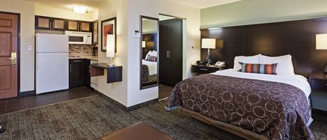Een hotelkamer met een bed, bureau, kitchenette en badkamer.