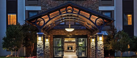 A hotel entrance with a stone facade, a covered entrance, and a fire feature.