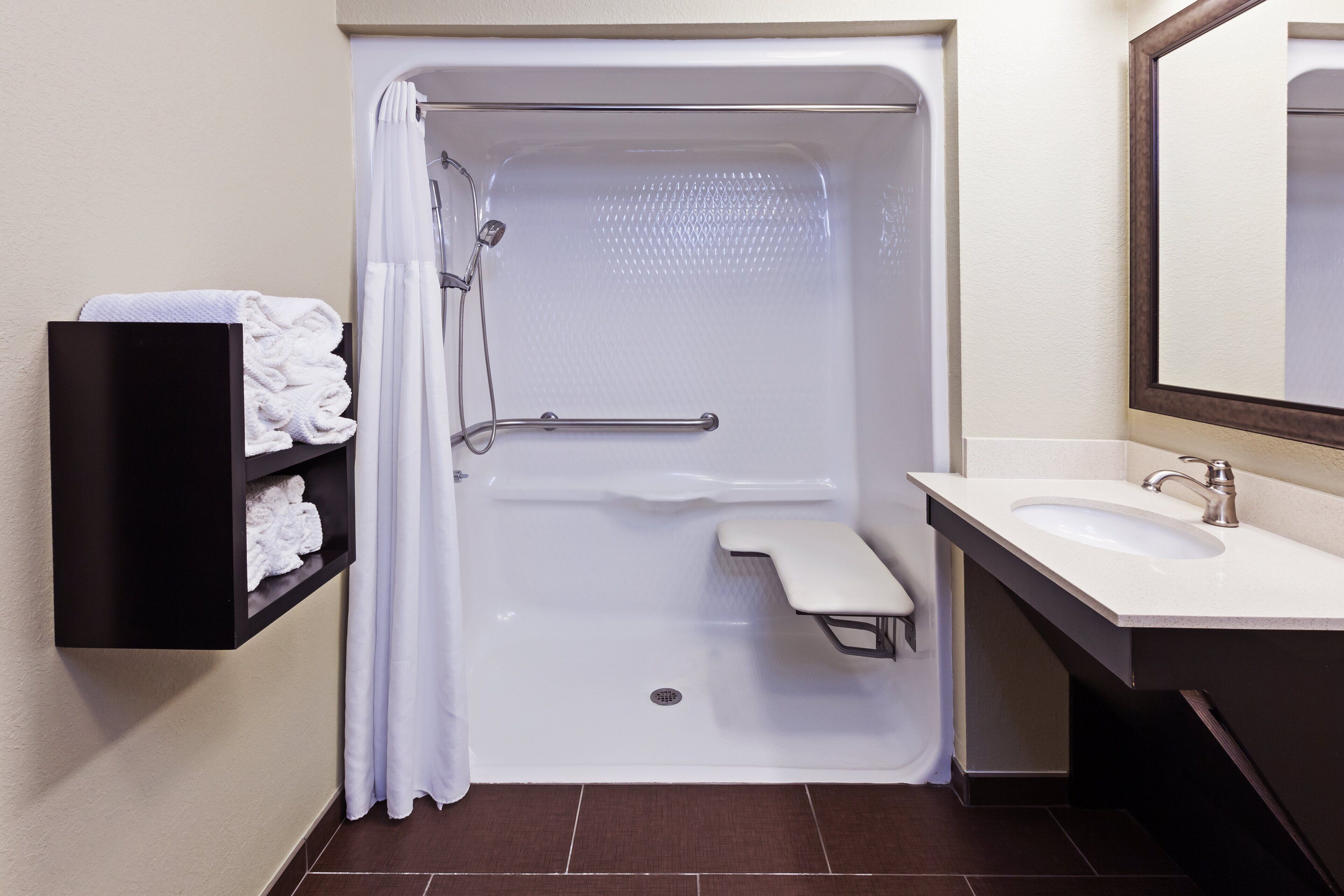 A bathroom with a shower, a sink, and a towel rack.