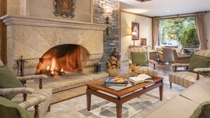 A cozy living room with a stone fireplace, comfortable seating, and a large window offering a view of the outdoors. - Hotel Vielha Val d'Arán, Affiliated by Meliá (Vielha e Mijaran)