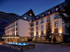 Un hôtel à plusieurs étages doté de balcons, d’une fontaine et d’un sapin de Noël.