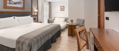 A hotel room with a large bed, a desk, and a chair. There is a television on the wall and a window with curtains.