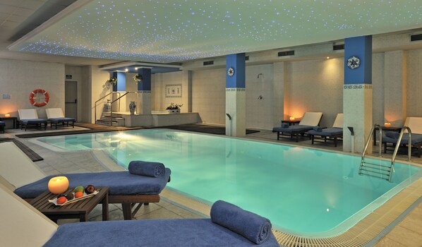A swimming pool with lounge chairs and a lifebuoy on the wall.