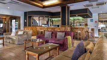 A spacious lobby with a bar area, wooden furniture, and a seating arrangement.