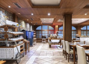 A cozy cafe with wooden interiors, a stone wall, and a large window. - Hotel Vielha Val d'Arán, Affiliated by Meliá (Vielha e Mijaran)