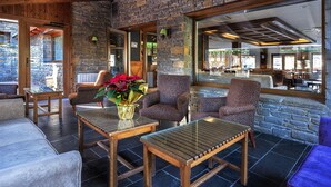 A cozy indoor seating area with stone walls, wooden furniture, and a large window offering a view of the interior. - Hotel Vielha Val d'Arán, Affiliated by Meliá (Vielha e Mijaran)