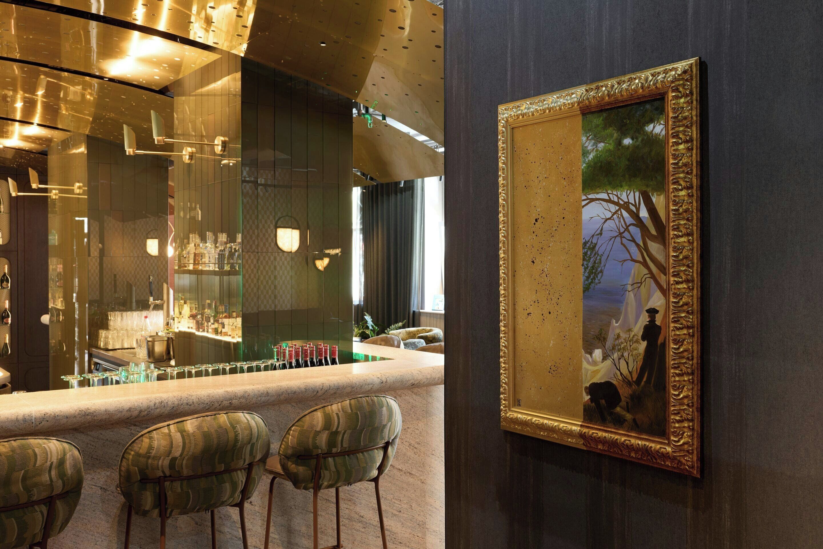 Un'area bar con un bancone in marmo, sgabelli da bar e un quadro appeso al muro.