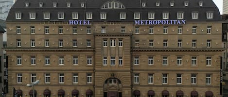 A large, historic building with two sections labeled "HOTEL" and "METROPOLITAN." It features a symmetrical facade with evenly spaced windows and a central entrance with a decorative arch.