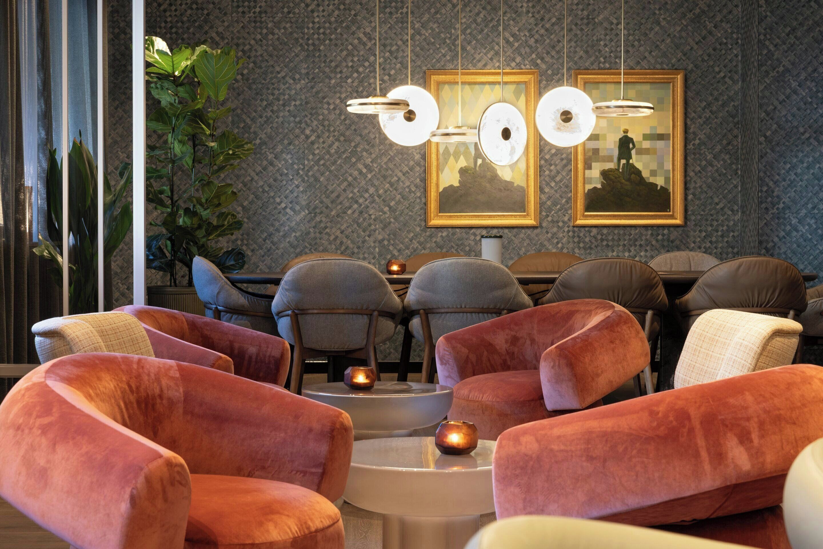 A modern lounge area with plush seating, pendant lighting, and framed artwork on the wall.