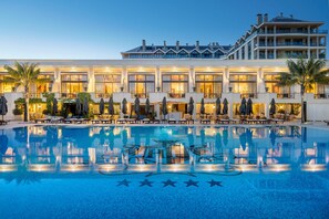 A hotel with a large pool, outdoor seating, and a well-lit facade. - Palácio Estoril Hotel, Golf & Wellness (Cascais)