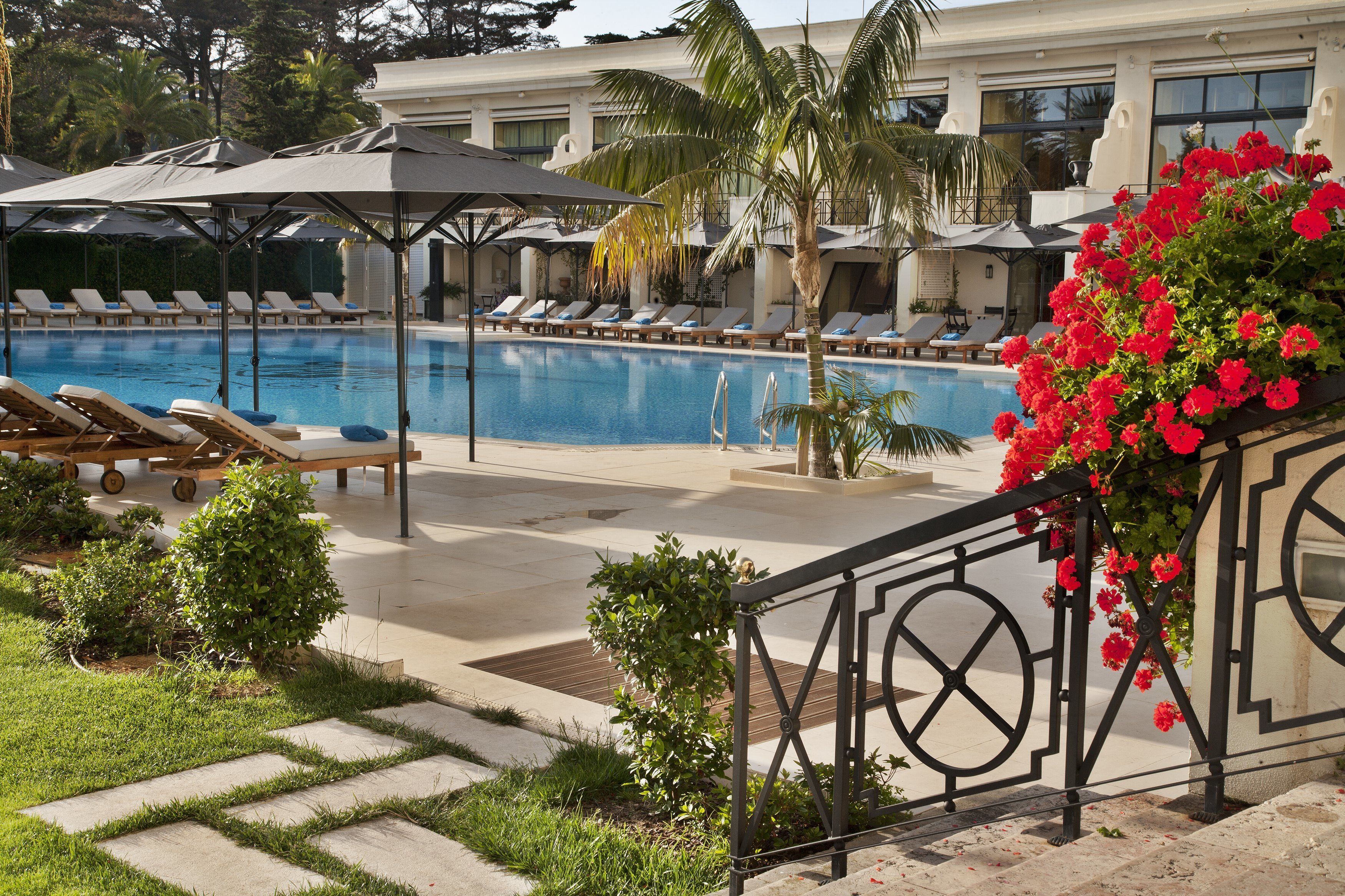 A pool area with lounge chairs, umbrellas, and a decorative flower arrangement.