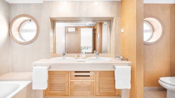 Un baño moderno con dos lavamanos, un espejo grande, armarios de madera y un inodoro.
