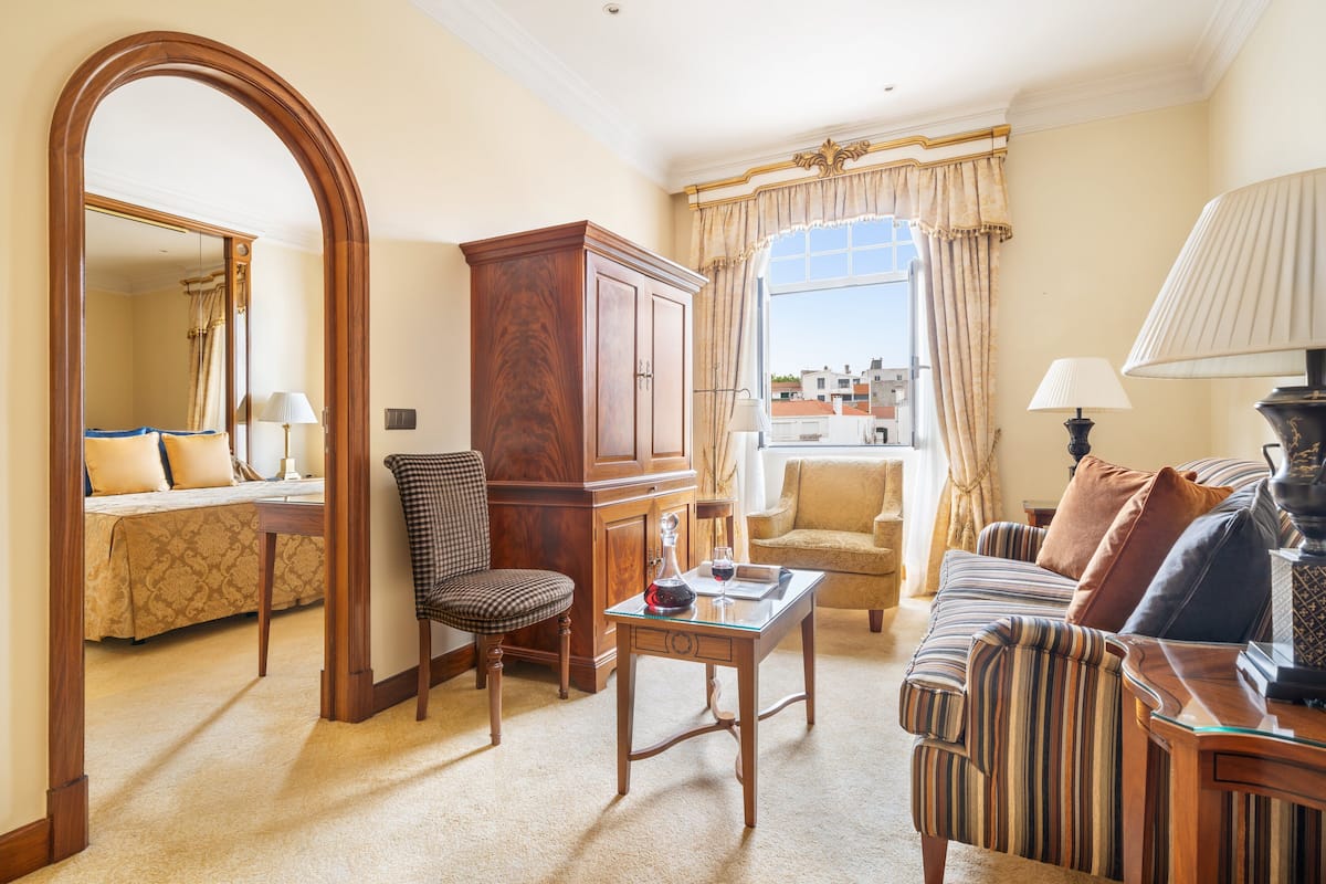 A well-furnished living room with a sofa, armchairs, a wooden cabinet, and a glass coffee table.