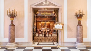 A grand entrance with a checkered floor, a chandelier, and a sign reading "four Seasons."