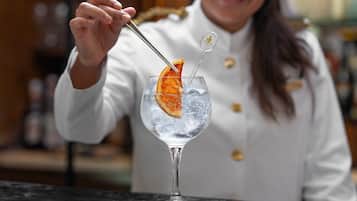 A bartender preparing a cocktail with an orange slice garnish.