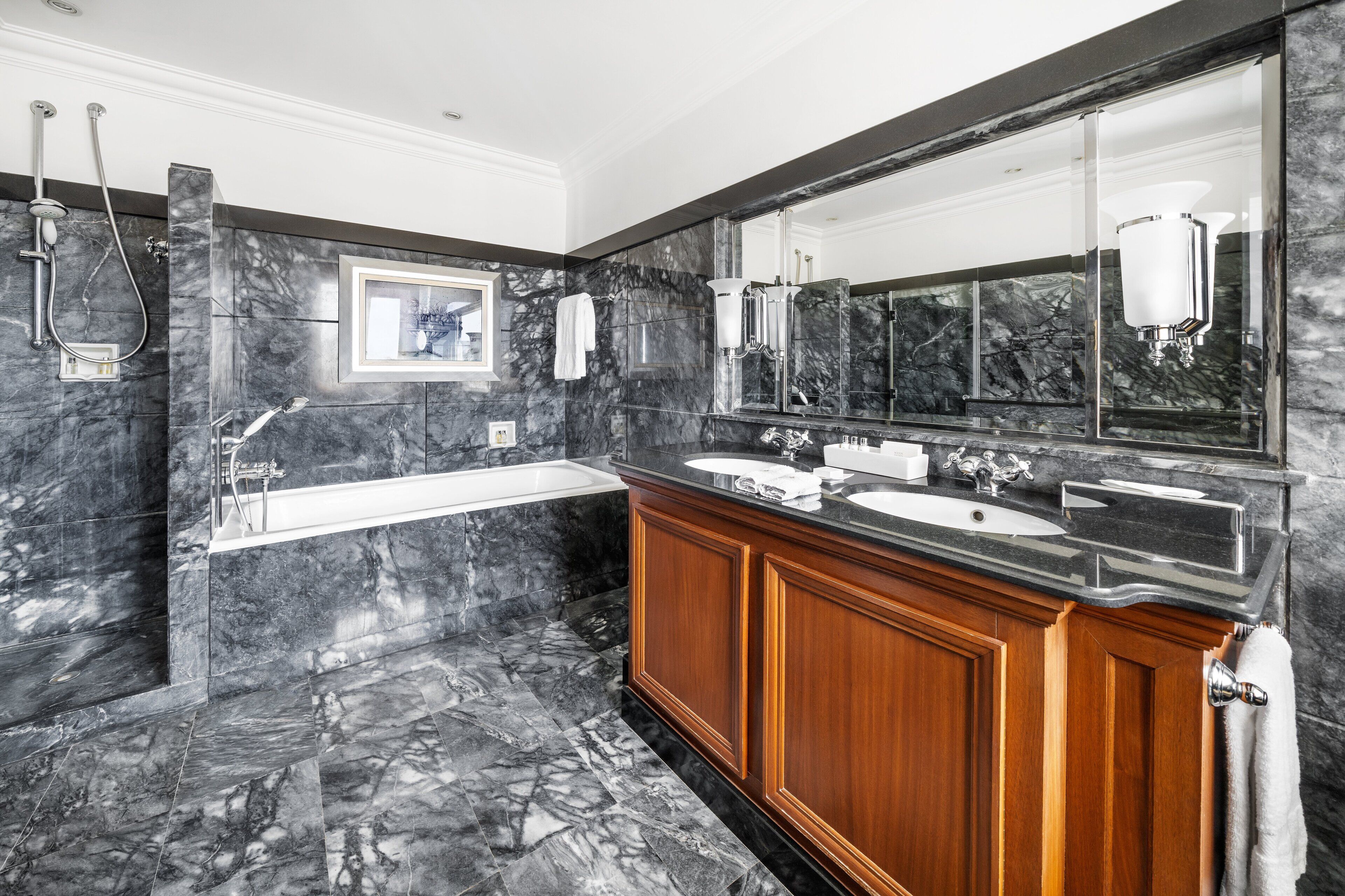 A modern bathroom with a marble floor, dual sinks, a large mirror, and a separate shower area.