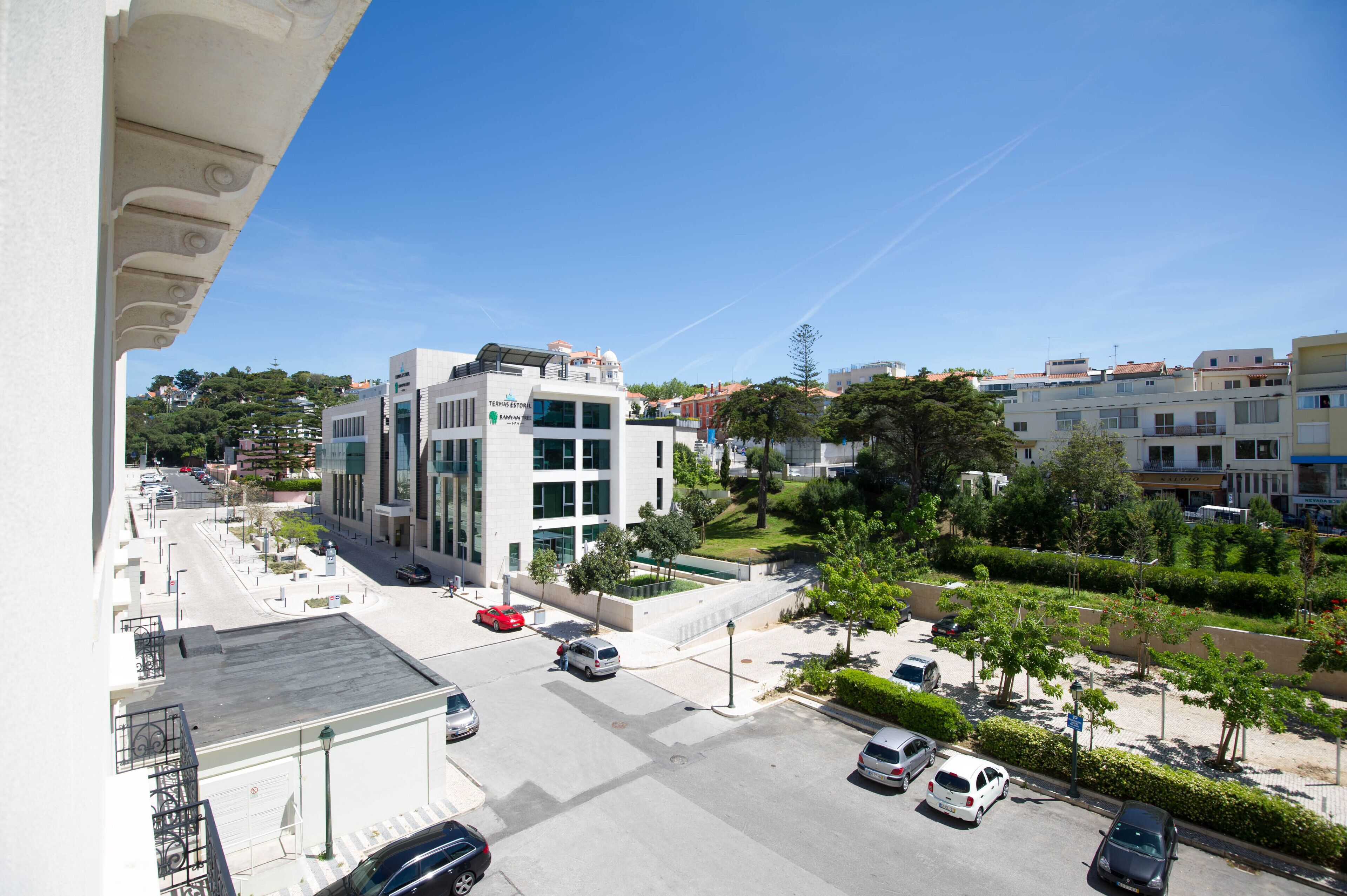 A modern building with a flat roof, large windows, and a parking lot with several cars.