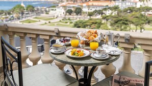 A balcony table with breakfast items, a newspaper, and a view of a cityscape.