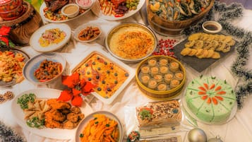 Una variedad de platos y postres sobre una mesa, incluyendo un gran guiso de carne, un pastel y varios cuencos con comida.