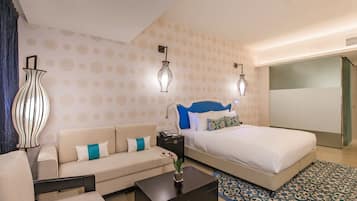 A hotel room with a bed, a sofa, a coffee table, and two wall-mounted lamps.