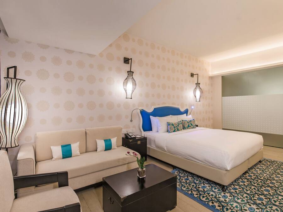 A hotel room with a bed, a sofa, a coffee table, and two wall-mounted lamps.