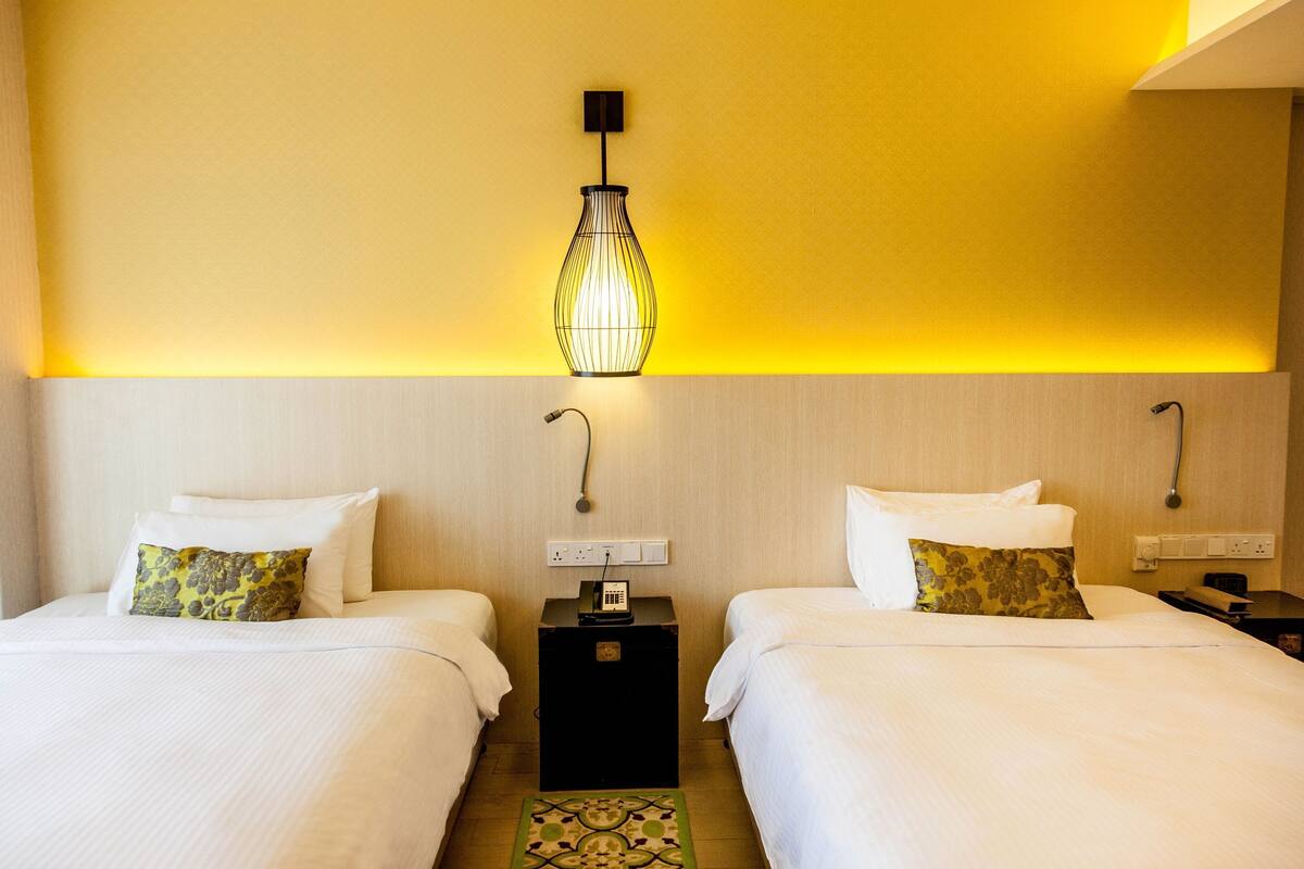 Ein Hotelzimmer mit zwei Betten, einem Nachttisch mit Telefon und einer Wandleuchte.