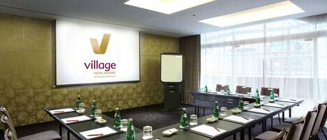 A conference room with a long table, chairs, and a presentation screen.