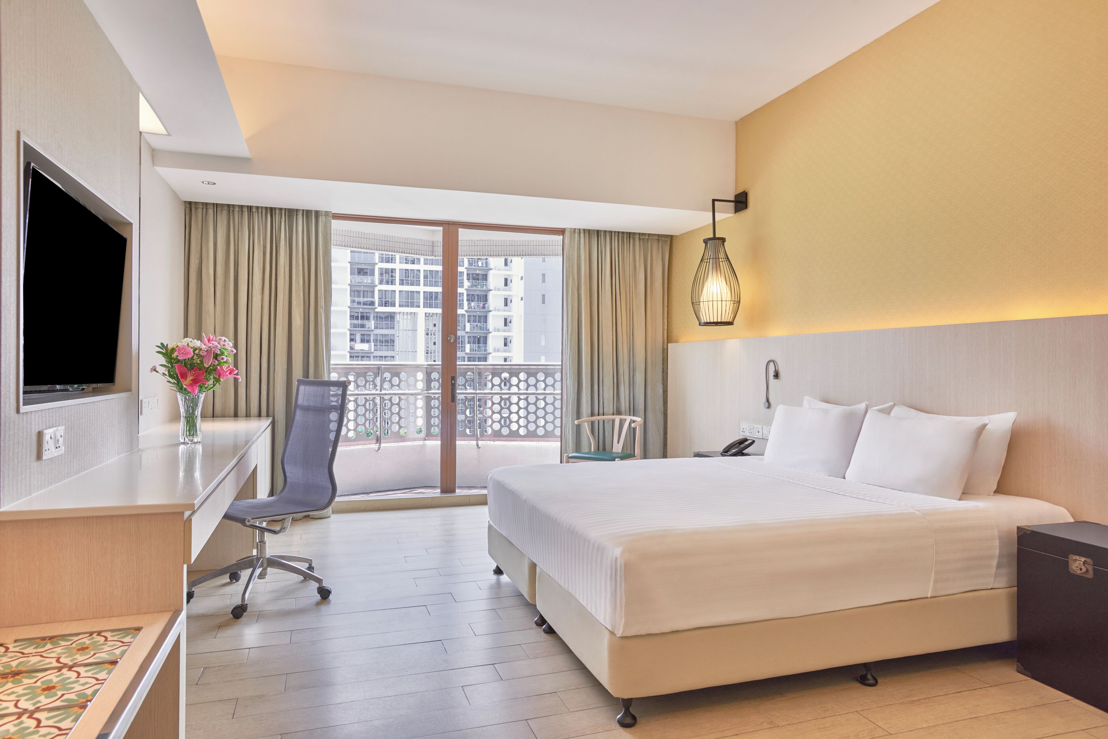 A hotel room with a bed, a desk, a chair, a TV, a phone, and a window with curtains.
