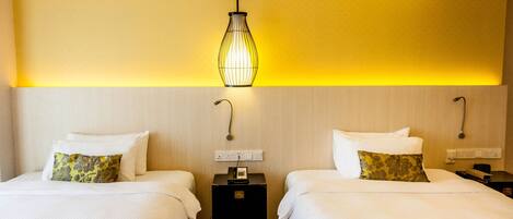A hotel room with two beds, a nightstand with a telephone, and a wall-mounted light fixture.