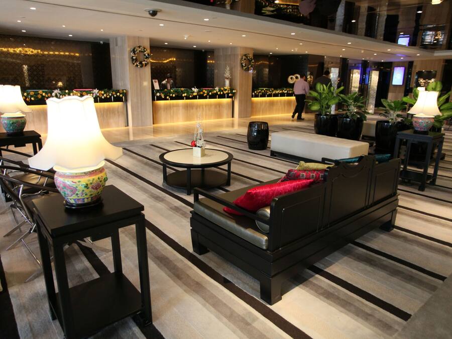 Een ruime lobby met een receptiebalie, zithoeken en decoratieve planten.