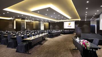 A conference room with rows of tables, chairs, and a podium with a floral arrangement.