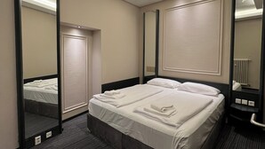 A hotel room with a large bed, a bedside table, a mirror, and a ceiling light fixture. - Adrett Hotel Königsallee (Düsseldorf)
