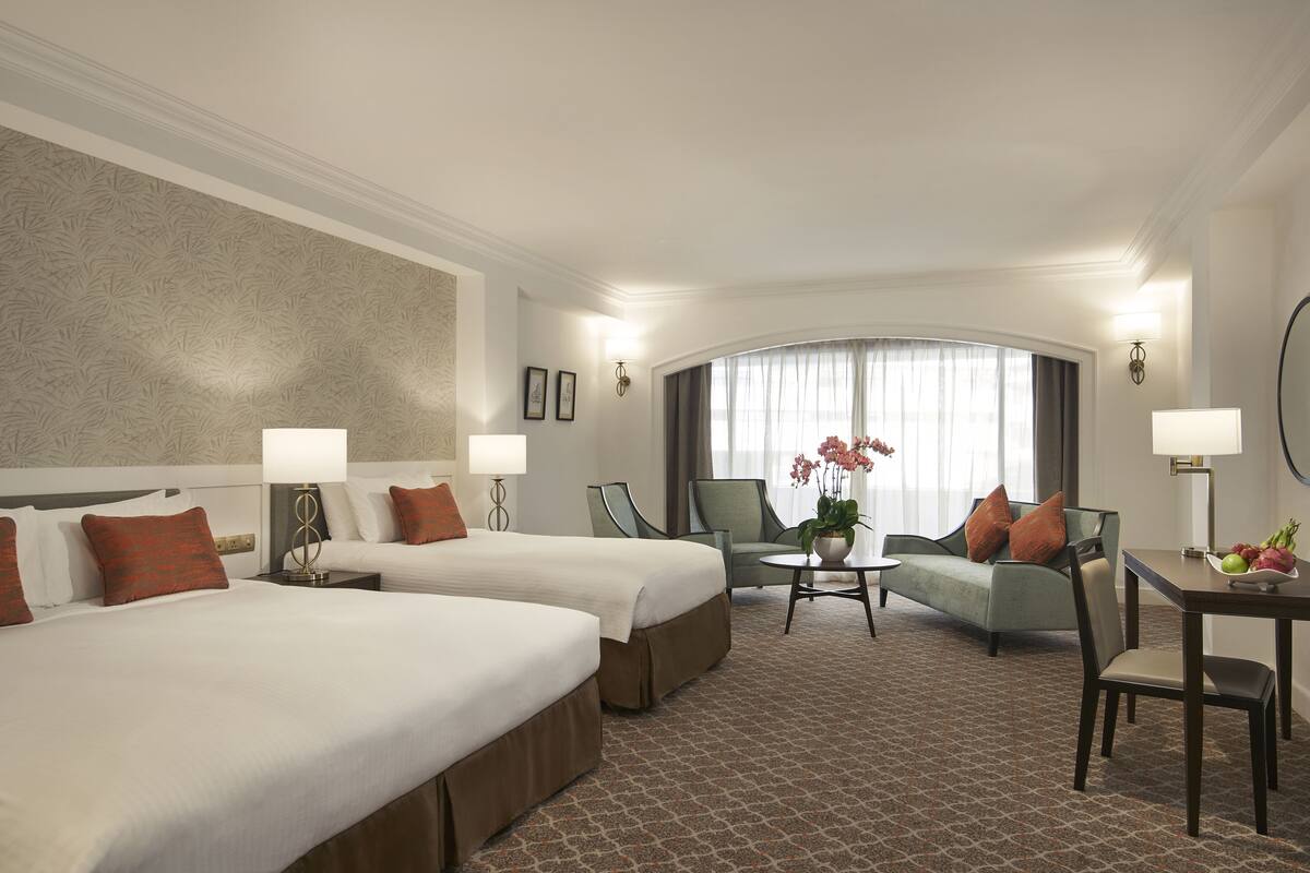 Une chambre d’hôtel avec deux lits, un canapé, une petite table et une table à manger.
