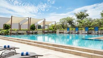 Una piscina al aire libre, sillones reclinables de piscina