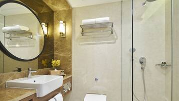 Un baño moderno con tocador de mármol, inodoro, ducha con mampara de vidrio y un espejo grande.