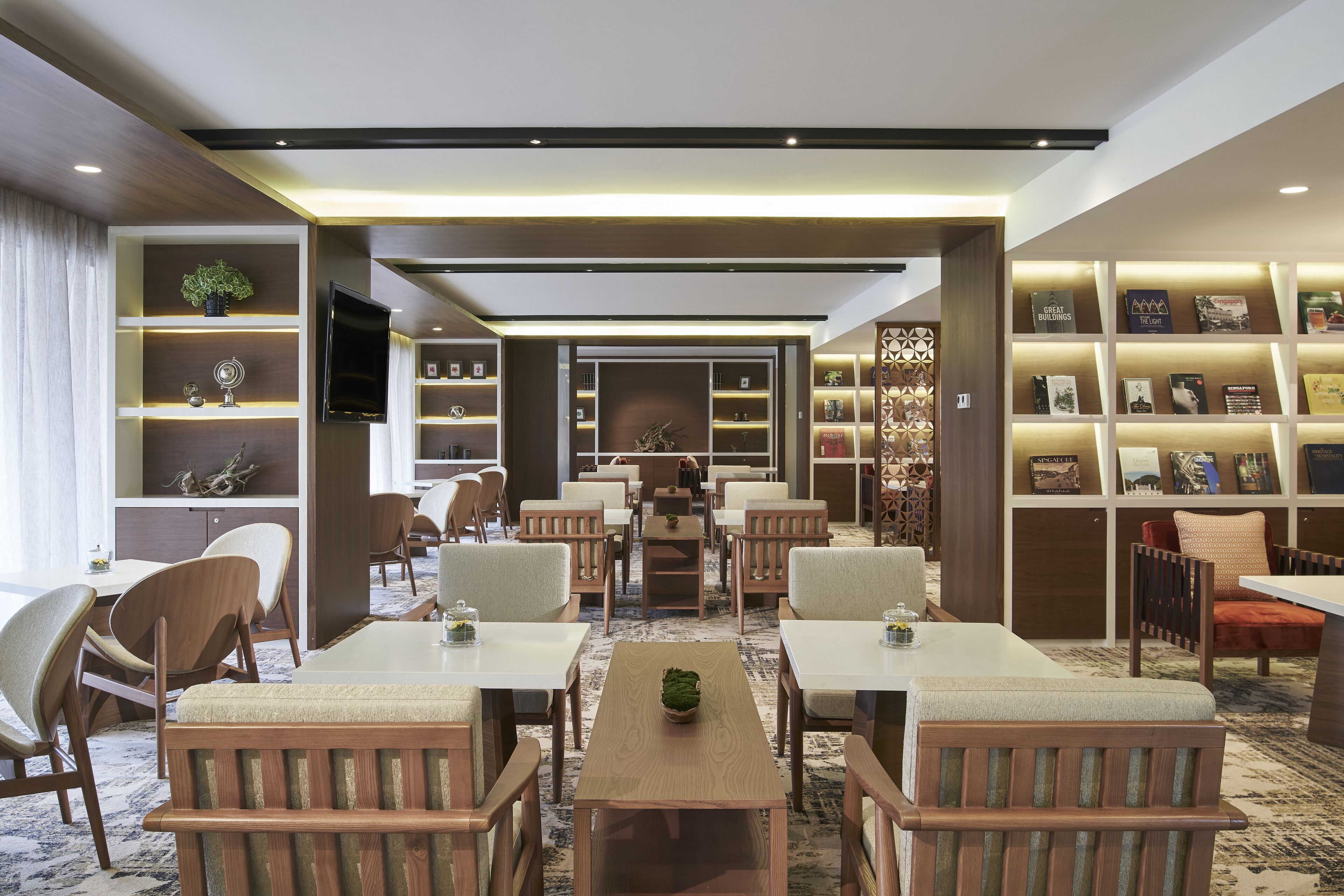A modern library with bookshelves, comfortable seating, and a central table.