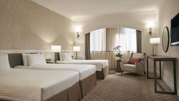 A hotel room with two beds, a chair, a small table, and a TV.