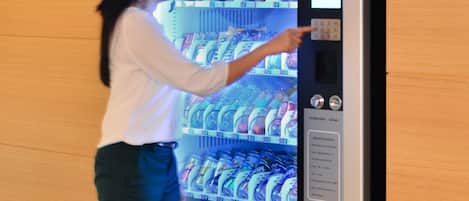 Una persona utilizando una máquina expendedora llena de diferentes bebidas.
