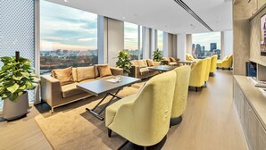 Una camera d'albergo moderna con vista sulla città, una zona divani, poltrone gialle e un'ampia finestra.