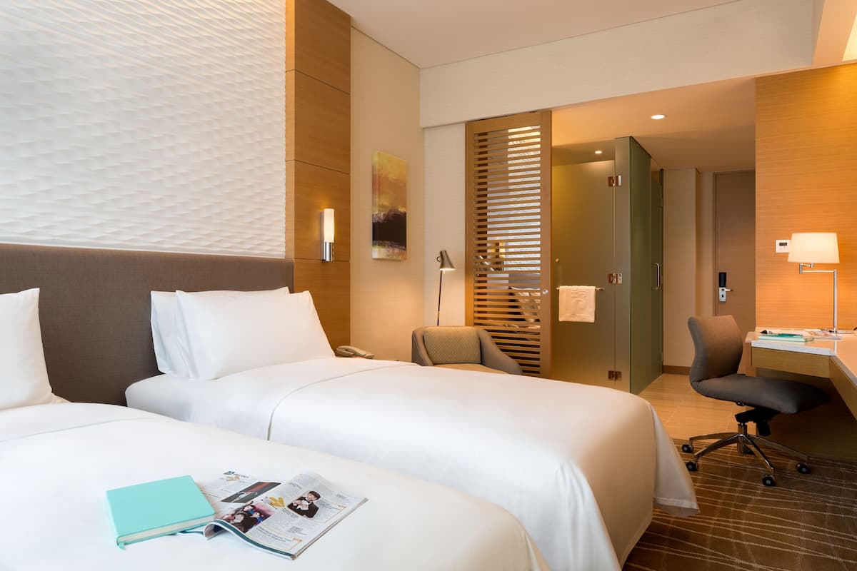 Habitación de hotel con dos camas, un escritorio y una silla.