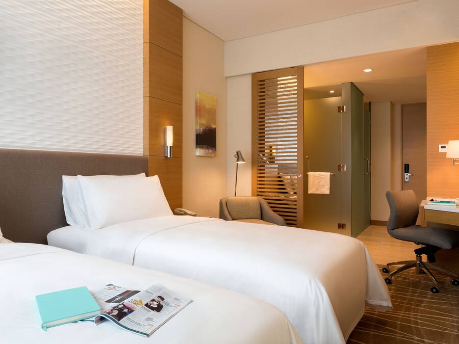 Habitación de hotel con dos camas, un escritorio y una silla.