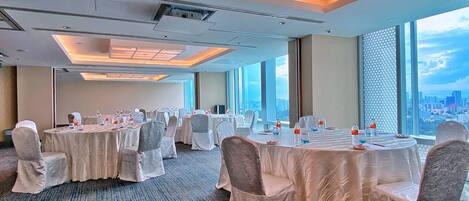 A conference room with round tables, chairs, and water bottles.