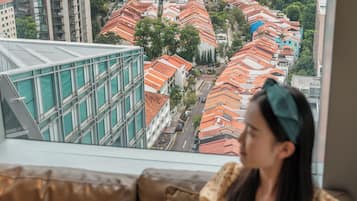 A person sitting on a brown sofa by a window with a city view.